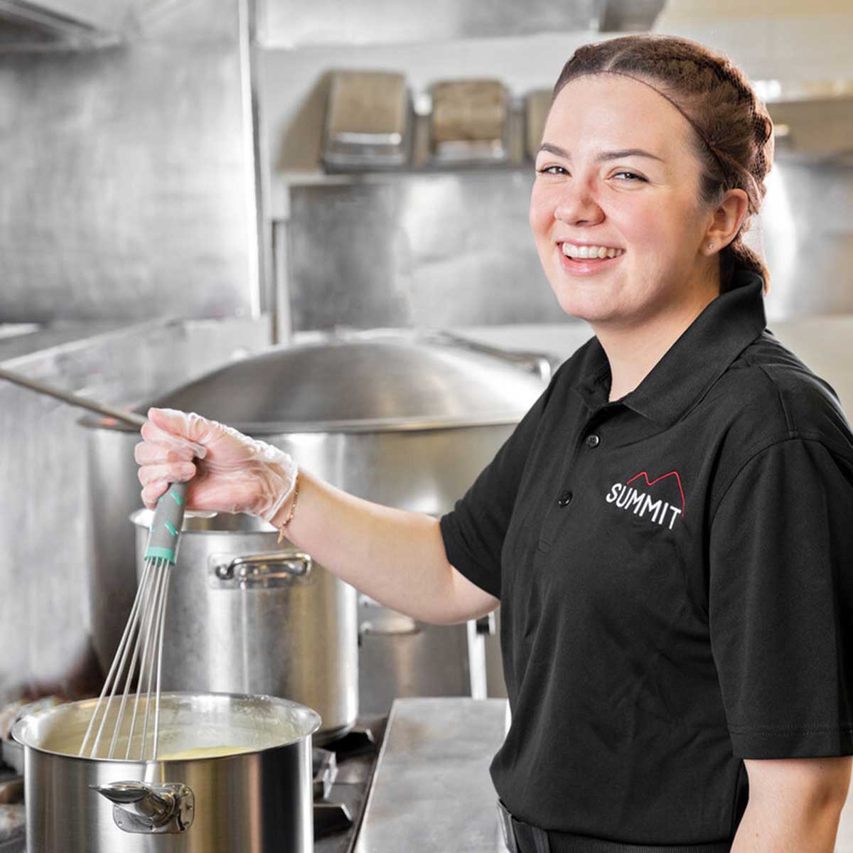 Employee smiling while stirring pot